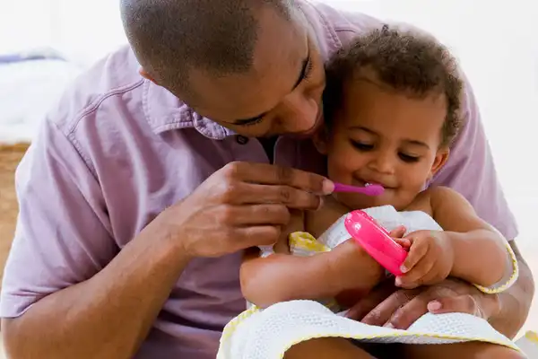Father brushing babys teeth