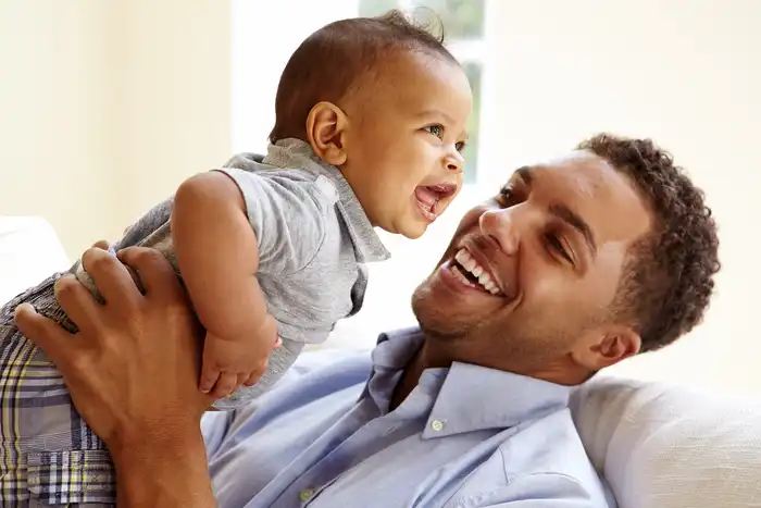 photo of proud father playing with baby boy